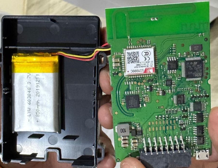 An external GPS tracking device, opened to show its battery and circuit board
